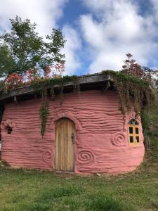 une grange rose avec une porte et des fleurs sur le toit dans l'établissement Sítio Monte Alegre, à Ibicoara