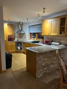 cocina con armarios de madera y encimera de piedra en 6 Canalside Apartments en Fort William