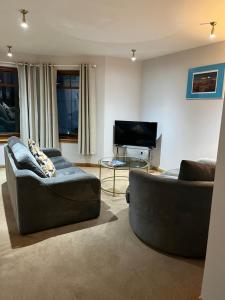 uma sala de estar com 2 sofás e uma televisão de ecrã plano em 6 Canalside Apartments em Fort William