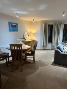 uma sala de estar com uma mesa e cadeiras e um sofá em 6 Canalside Apartments em Fort William