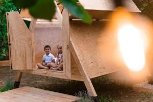 2 enfants assis dans une maison de jeu en bois dans l'établissement SKY HOUSE EXPERIENCE, à Salmore