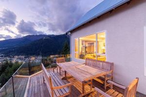 a deck with a wooden table and benches on a house at Nyumbani - Elevated Lake and Mountain Views in Queenstown