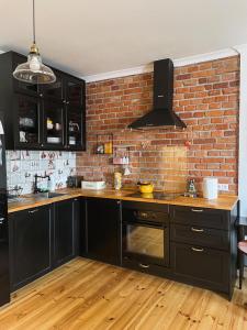 a kitchen with black cabinets and a brick wall at Ratuszowa 18 in Olsztynek