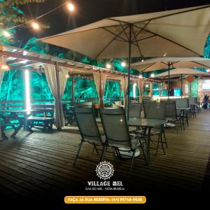 a group of tables and chairs with umbrellas on a deck at Pousada Village Mel in Ilha do Mel