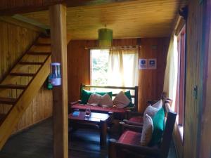 a living room with a couch and a staircase at Hostal Quillelhue in Pucón