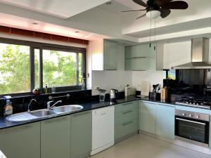 a kitchen with white cabinets and a ceiling fan at Andaman Hills - panoramic sea view house in Patong in Patong Beach