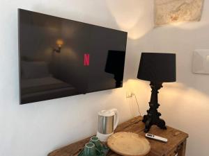 un televisor en una pared con una lámpara en una mesa en Nobile Dimora di Puglia en Ostuni