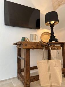 un televisor en una mesa con una lámpara y una bolsa en Nobile Dimora di Puglia, en Ostuni