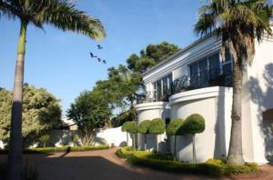 un edificio blanco con una palmera al lado en Luxury Beach Apartments, en Amanzimtoti