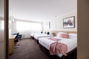 a hotel room with two beds and a desk at Central Caleula Motor Lodge in Orange