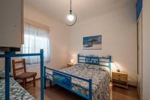1 dormitorio con 1 cama azul y 1 silla en Villa Susy, en Punta Prosciutto