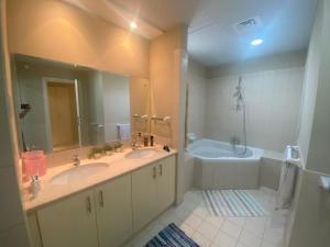bagno con 2 lavandini, vasca e specchio di Spacious 4-bedroom villa, children friendly a Dubai