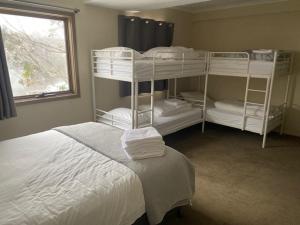 a bedroom with two bunk beds and a window at Winterbrook Chalet in Mount Buller