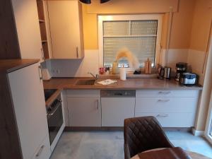 a kitchen with white cabinets and a sink and a window at Boddenkieker 14 in Zingst +9 photos