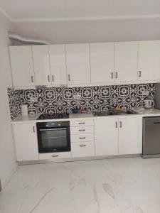 a kitchen with white cabinets and a black and white wallpaper at Alexandra's Apartments - Port of Zante in Zakynthos Town