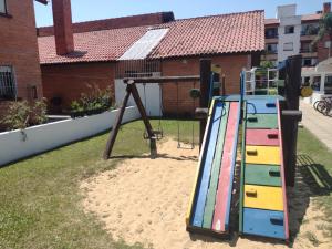een speeltuin met een glijbaan in het zand bij Apartamento Morada das Petúnias in Capão da Canoa
