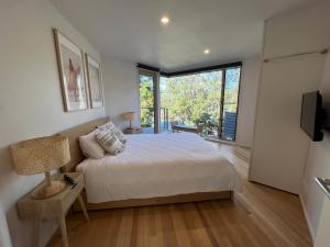 a bedroom with a bed and a large window at Architect designed 4 bedroom with ocean views from every room in Lorne
