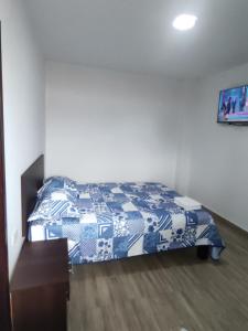 1 dormitorio con 1 cama con manta azul y blanca en HOSTAL PARIS, en Manta