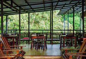 un restaurante con mesas de madera y sillas en una terraza en Cabinas Villa Drake, en Drake