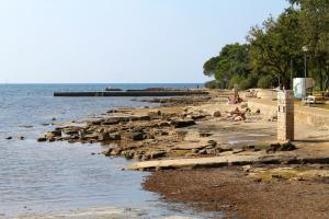 uma praia com pedras e pessoas sentadas na praia em Studio Dolinci 7111a em Umag