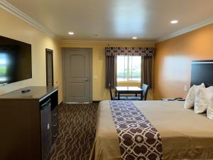 a hotel room with a bed and a flat screen tv at Industry Inn & Suites in La Puente