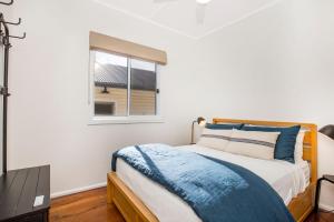 1 dormitorio con cama y ventana en Fishery Road Cottage Pet Friendly 2 Mins Walk to Beach en Currarong