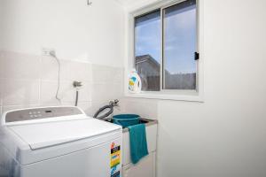 a laundry room with a washing machine and a window at Fishery Road Cottage Pet Friendly 2 Mins Walk to Beach in Currarong +27 photos