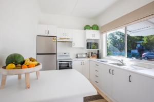 a white kitchen with a bowl of fruit on the counter at Fishery Road Cottage Pet Friendly 2 Mins Walk to Beach in Currarong