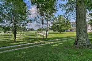 una recinzione bianca e alberi di fronte a una casa di Renovated Bunkhouse on 12-Acre Horse Farm! 