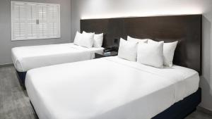two beds in a hotel room with white pillows at Hollywood Inn Express LAX in Inglewood