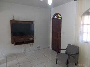 uma sala de estar com uma televisão, uma cadeira e uma janela em Casa de praia em Guarapari - Santa Mônica. em Guarapari