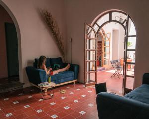 a woman sitting on a couch in a living room with a laptop at Coliving Chingon in Guadalajara