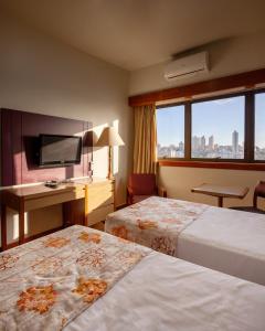 Cette chambre comprend deux lits et une télévision. dans l'établissement Hotel Nacional Inn Belo Horizonte, à Belo Horizonte