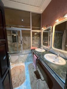 a bathroom with two sinks and two mirrors at Magnifique villa avec un grand jardin et une cascade in Agadir