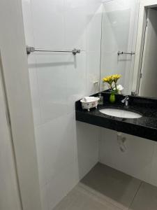 uma casa de banho branca com um lavatório e um espelho em Pousada Dona Terezinha em Formiga