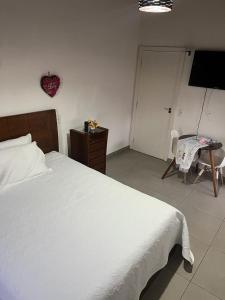 a bedroom with a bed and a table and a television at Pousada Dona Terezinha in Formiga