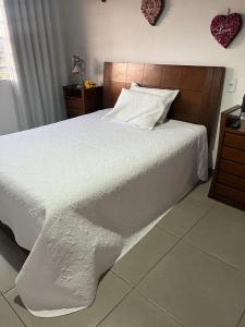 a bedroom with a white bed with a wooden headboard at Pousada Dona Terezinha in Formiga