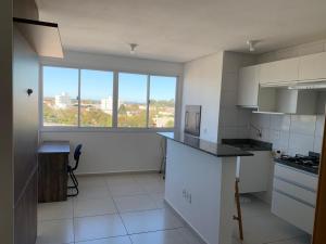 a kitchen with white appliances and a large window at Novo apto com 100 metros da Av. Brasil in Passo Fundo