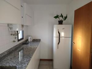 a kitchen with a white refrigerator with a potted plant on top at Aparts Kodu- Residencia Familiar in Río Cuarto
