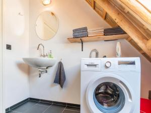 een badkamer met een wasmachine en een wastafel bij Farmhouse in Staphorst with sauna in Rouveen