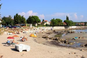 a beach with people and umbrellas and people on the sand at Apartments by the sea Zambratija, Umag - 7030 in Zambratija