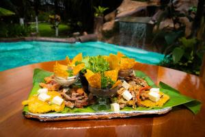 un plato de comida en una mesa junto a una piscina en Hotel & Hot Springs Sueño Dorado en Fortuna