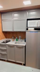 a kitchen with a sink and a refrigerator at Lindo Apart Lake Side com banheira in Brasilia