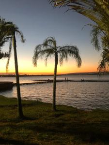 two palm trees on the beach at sunset at Lindo Apart Lake Side com banheira in Brasilia