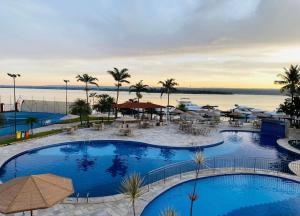 a hotel with two pools and a view of the water at Lindo Apart Lake Side com banheira in Brasília