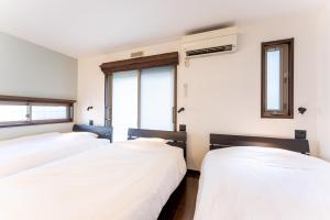 two beds in a room with two windows at 箱寝荘 - Hakoneso in Hakone