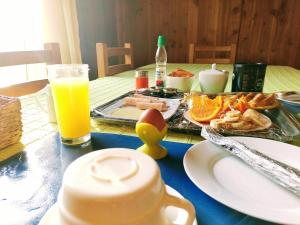 a table with a plate of food and a glass of orange juice at Hostal Quillelhue in Pucón