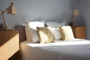 Una cama con sábanas blancas y almohadas. en Hôtel Courtille de Solutré, en Solutré-Pouilly