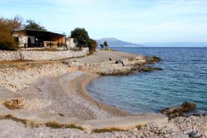a beach with a house and the water at Apartments with a parking space Ravni, Labin - 7613 in Ravni