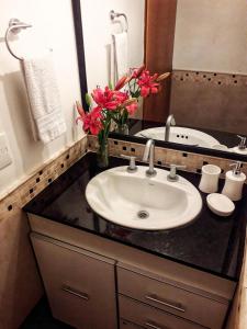 a bathroom with a sink and a mirror and flowers at Casa Roca in San Carlos de Bariloche